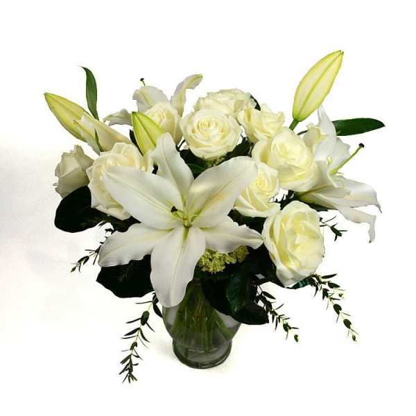 White lilies and roses arranged in a glass vase