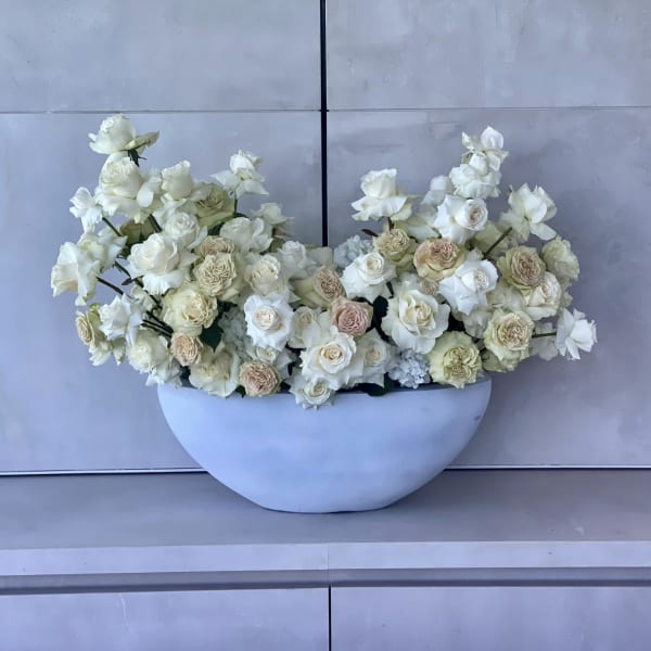 White and blush roses arranged in a white bowl-shaped vase