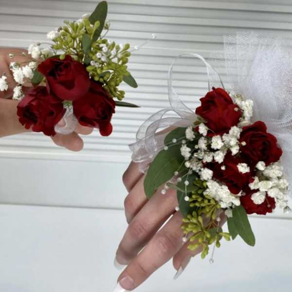 Red rose corsages with white baby's breath and tulle ribbon