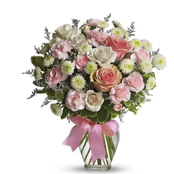 Pink and white rose bouquet in a glass vase with a pink ribbon