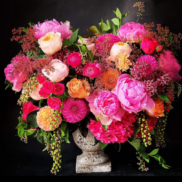Large pink and peach floral arrangement in a stone vase
