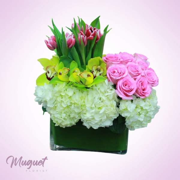 Pink roses, green orchids, tulips, and white hydrangeas in a square vase