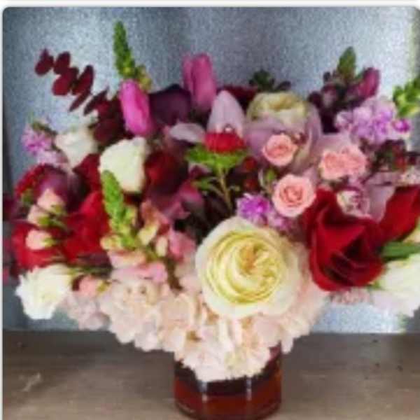 Mixed bouquet of roses and other blooms in a glass vase