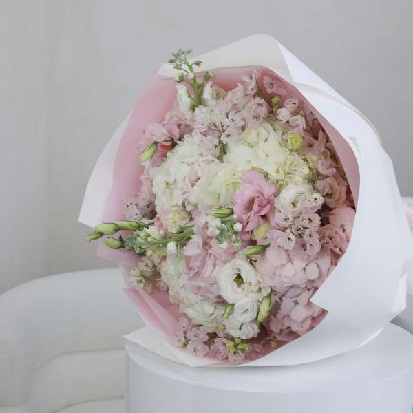 Bouquet of pale pink and white flowers wrapped in pink and white paper