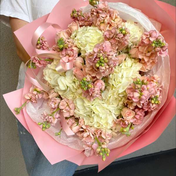 Bouquet of pale pink and cream flowers wrapped in pink paper