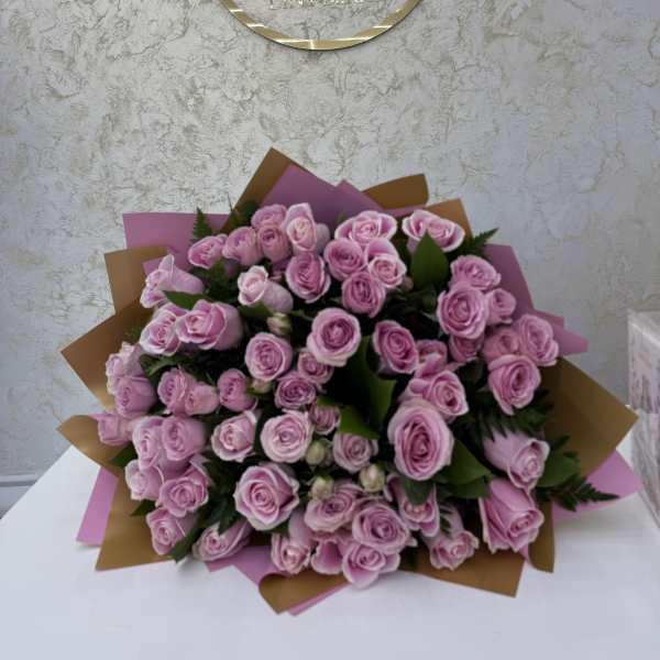 Large bouquet of pink roses wrapped in pink and brown paper