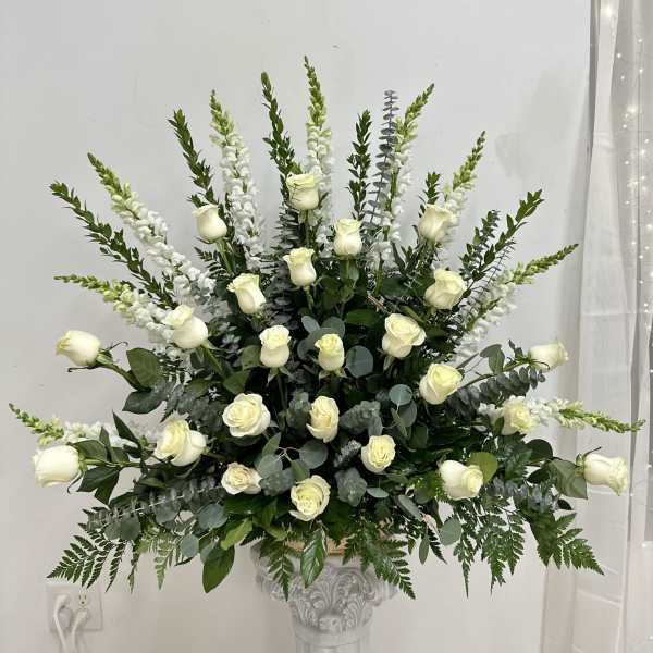 White roses and tall white snapdragons in a decorative pedestal vase