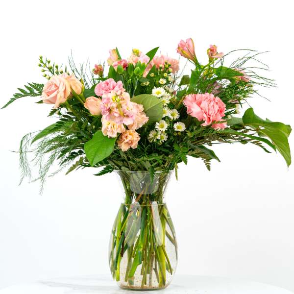 Pink and peach mixed flowers with white daisies arranged in a clear glass vase