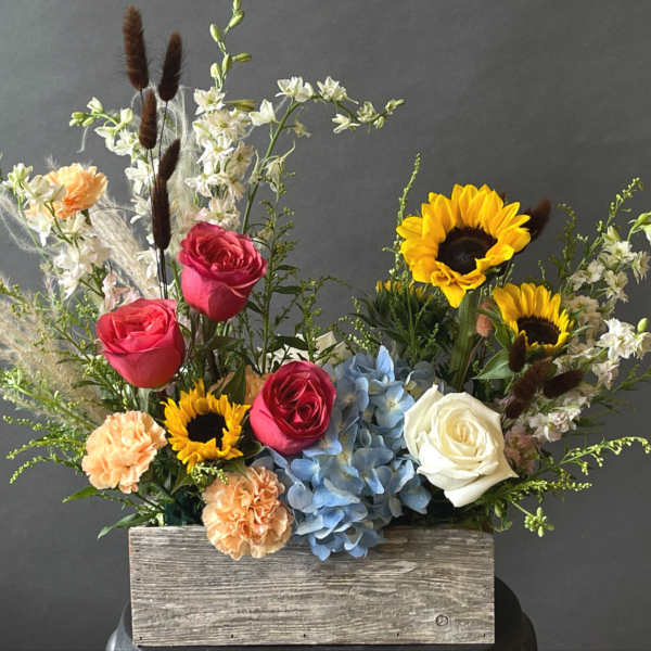 Mixed bouquet in a wooden box with roses, sunflowers, hydrangea, and carnations