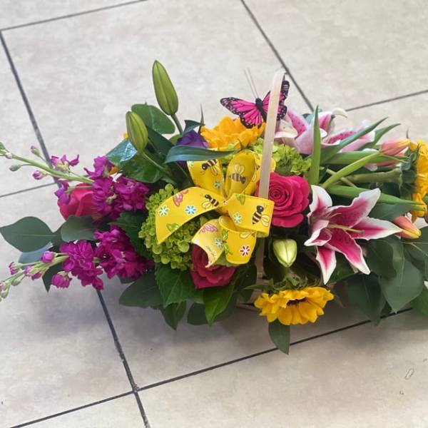 Colorful mixed flower basket with lilies, roses, and a yellow ribbon