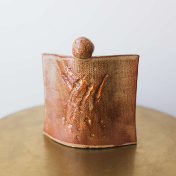Small ceramic vessel with a textured copper-brown glaze and rounded top