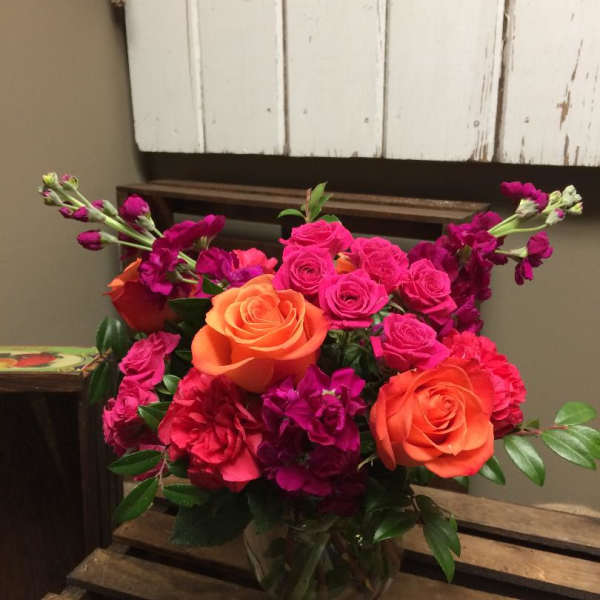 Bouquet of orange and pink roses in a clear glass vase