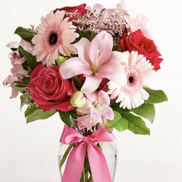 Pink and red mixed bouquet in a glass vase with a pink ribbon