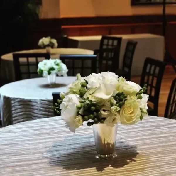 White and pale green floral centerpiece in a clear vase