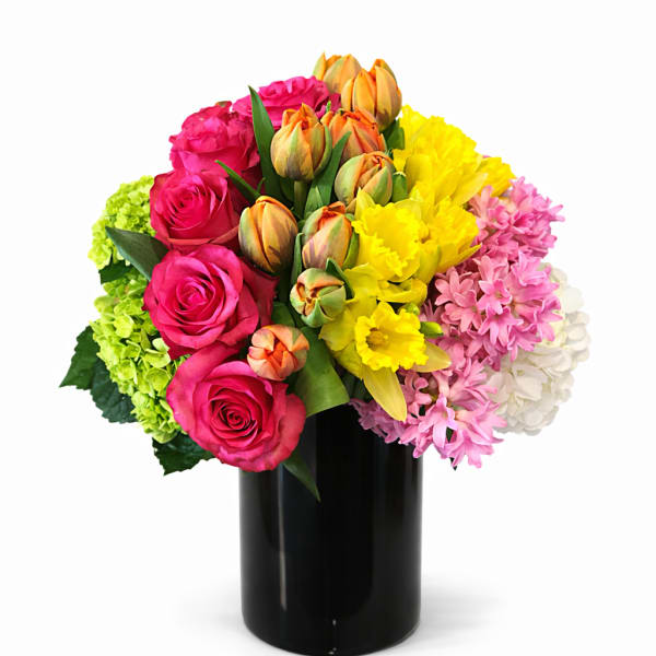 Bright mixed bouquet of roses, tulips, daffodils, and hyacinths in a black vase