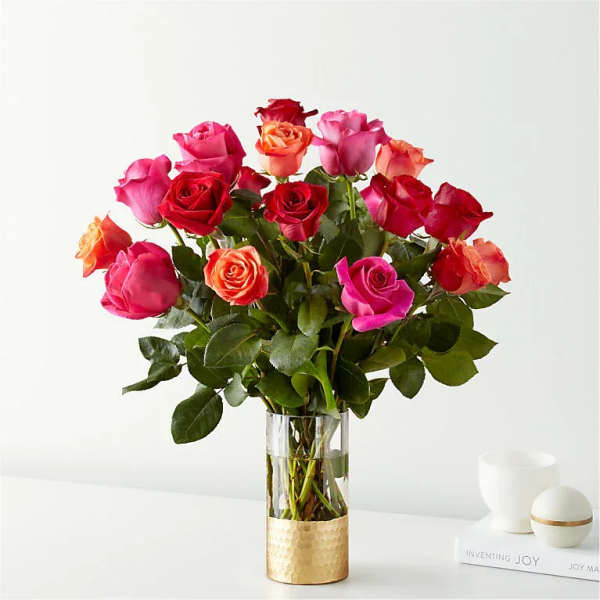 Bouquet of pink, red, and orange roses in a clear glass vase