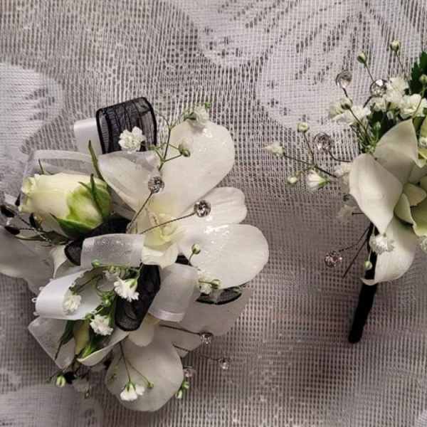 Two white orchid boutonnieres with black and white ribbon accents