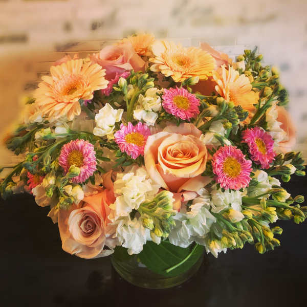 Peach roses and pink daisies in a glass vase