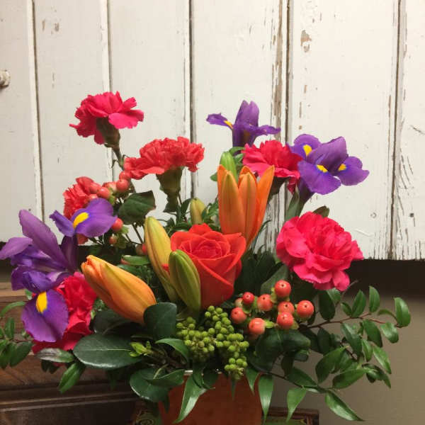Colorful bouquet with roses, lilies, irises, and carnations in a copper vase