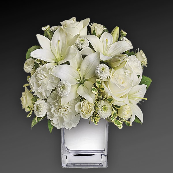 White floral arrangement in a clear square vase