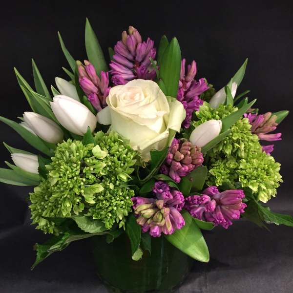 White rose and purple flowers in a glass vase