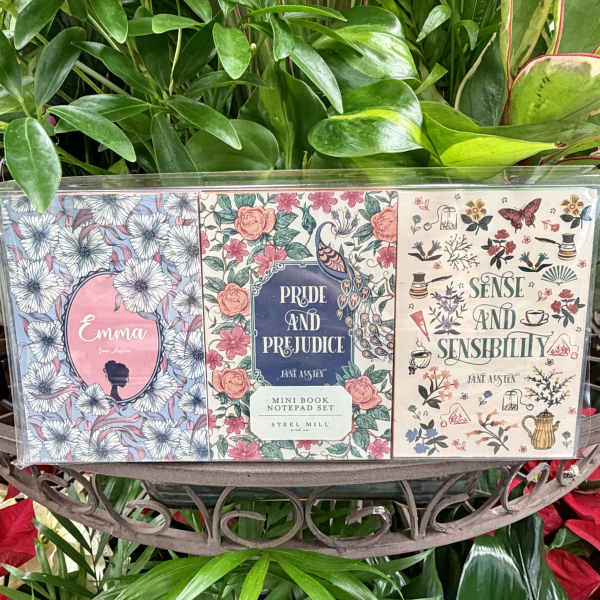 Three floral-themed mini notepads in a clear package on a plant display.