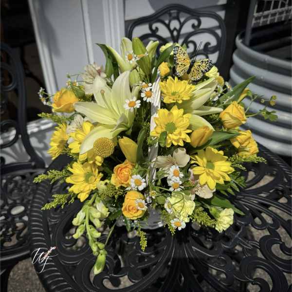 Yellow and cream floral arrangement with lilies, roses, and daisies