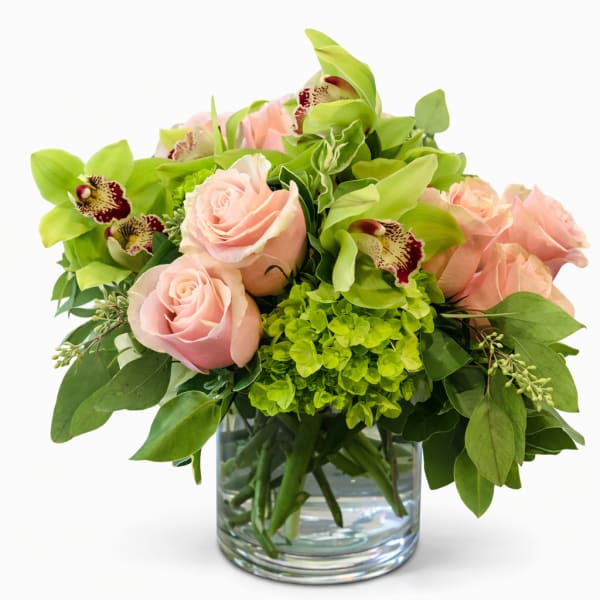Pink roses and green orchids arranged in a glass vase