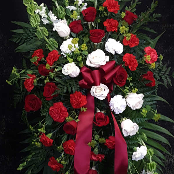 Standing floral spray with red and white roses and carnations on a black background