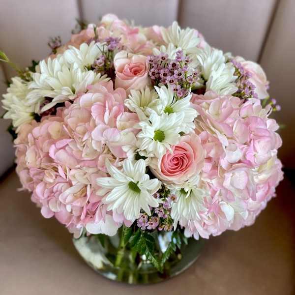 Pink and white bouquet with roses, hydrangeas, and daisies in a glass vase
