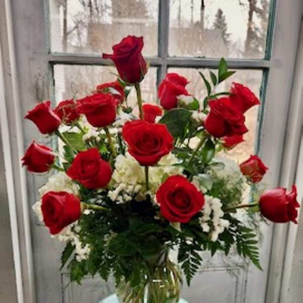 Bouquet of red roses and white filler flowers in a clear glass vase