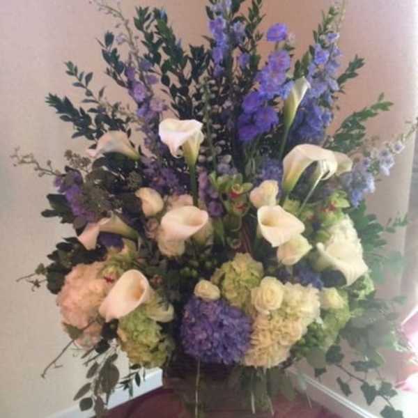 Tall floral arrangement with white calla lilies and purple blooms