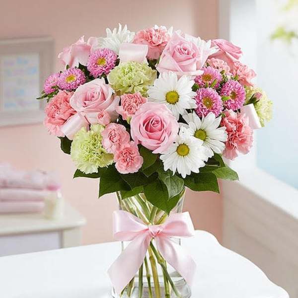 Pink and white mixed bouquet in a glass vase with a pink ribbon