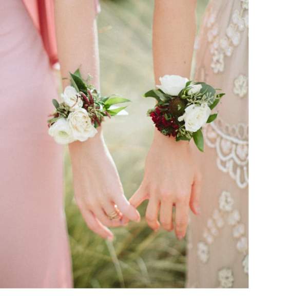 Two women wearing floral wrist corsages at a wedding