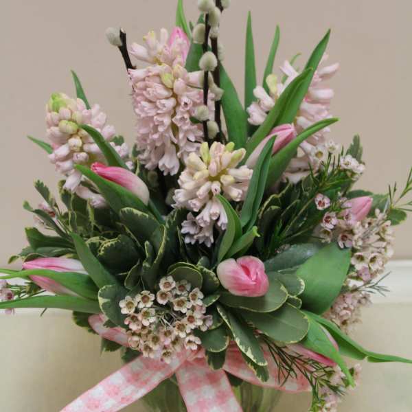 Pink tulips and pale hyacinths in a glass vase with a pink ribbon