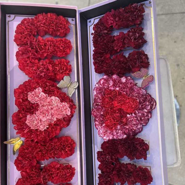 Two open gift boxes filled with red and pink carnation letters