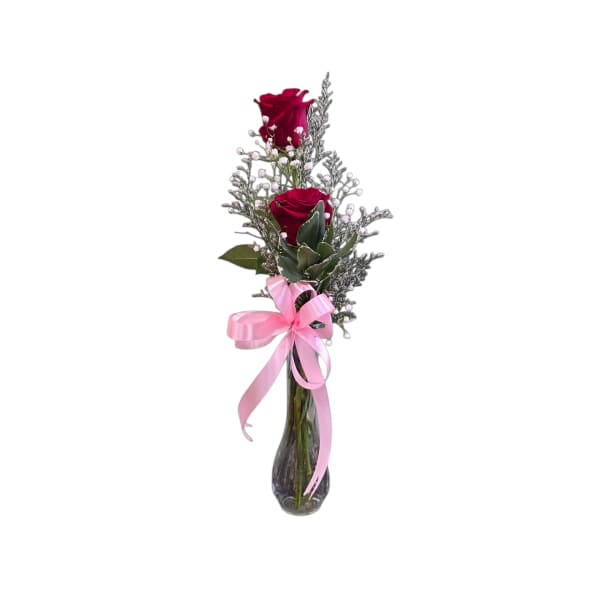 Two red roses in a glass vase with a pink ribbon