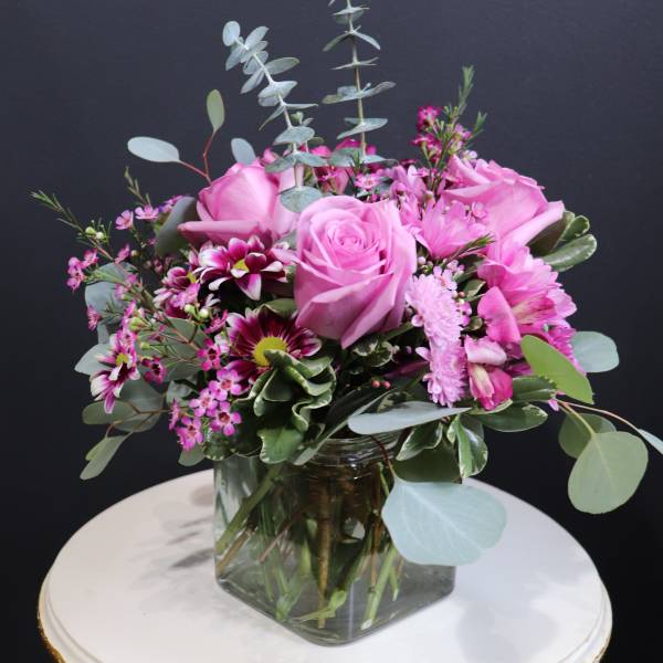 Pink roses and mixed blooms in a square glass vase