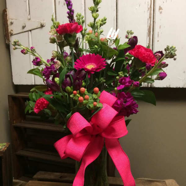Pink and purple mixed bouquet in a glass vase with a bright ribbon