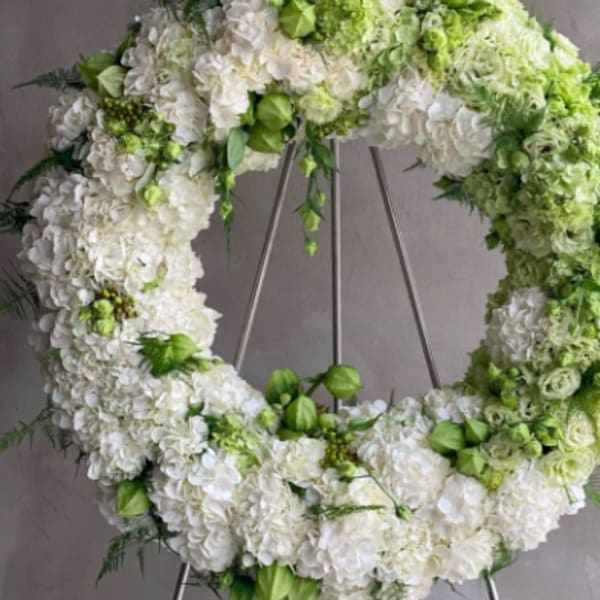 White and green floral wreath on a metal stand