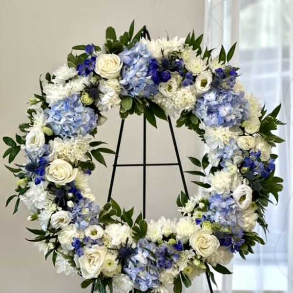 Blue and white floral wreath on a black stand
