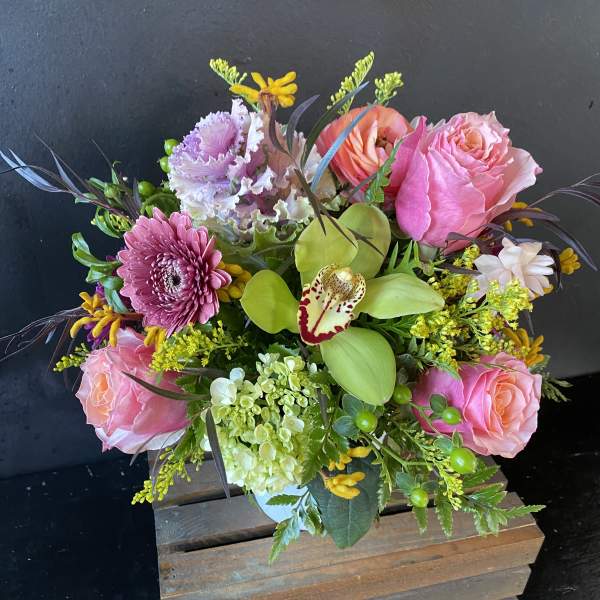 Pink roses and mixed blooms in a wooden box arrangement