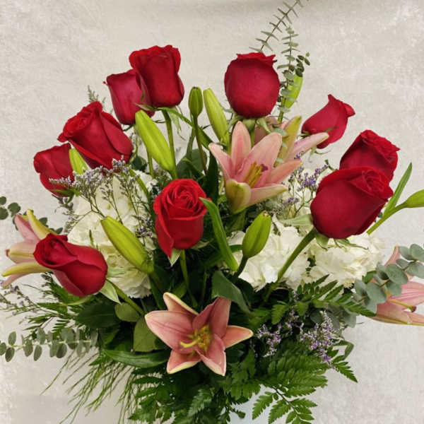 Red roses and pink lilies in a clear glass vase
