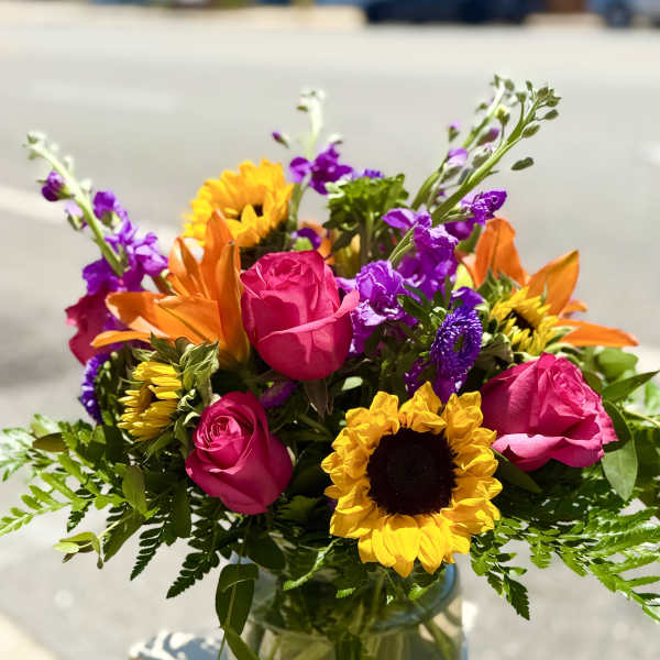 Bright mixed bouquet of roses and sunflowers in a glass vase