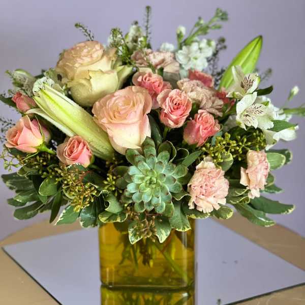 Pink roses and lilies arranged in a yellow glass vase