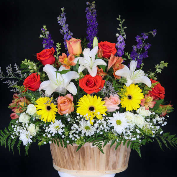 Mixed bouquet with roses, lilies, and daisies in a wooden basket