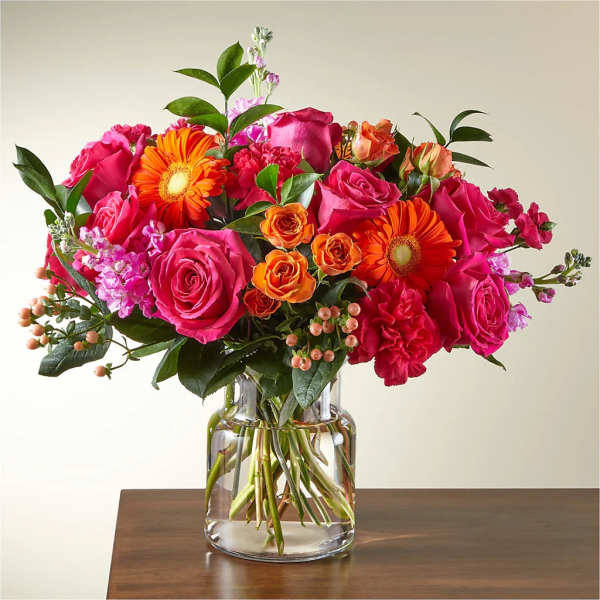 Bright mixed bouquet of pink and orange flowers in a clear glass vase