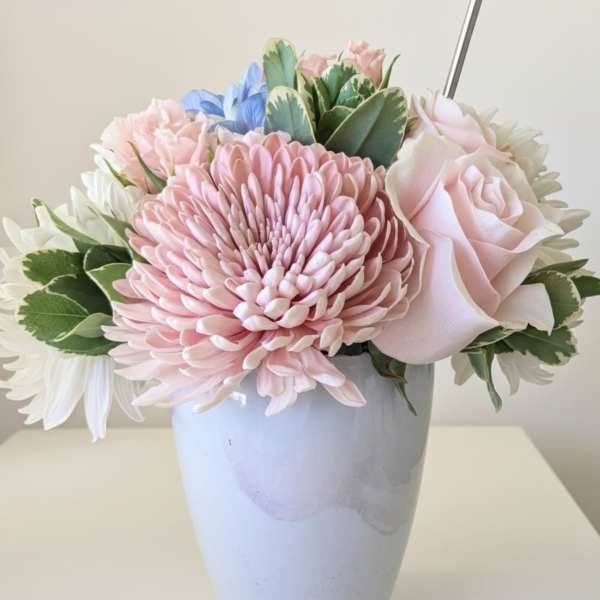 Pastel arrangement of pink chrysanthemum, rose, and white flowers in a light blue vase