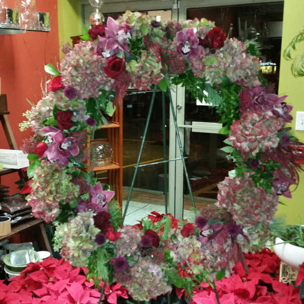 Large floral wreath with pink, purple, and red blooms on a stand