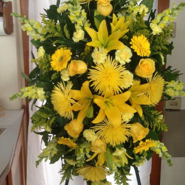 Tall yellow floral standing spray with lilies, roses, and daisies